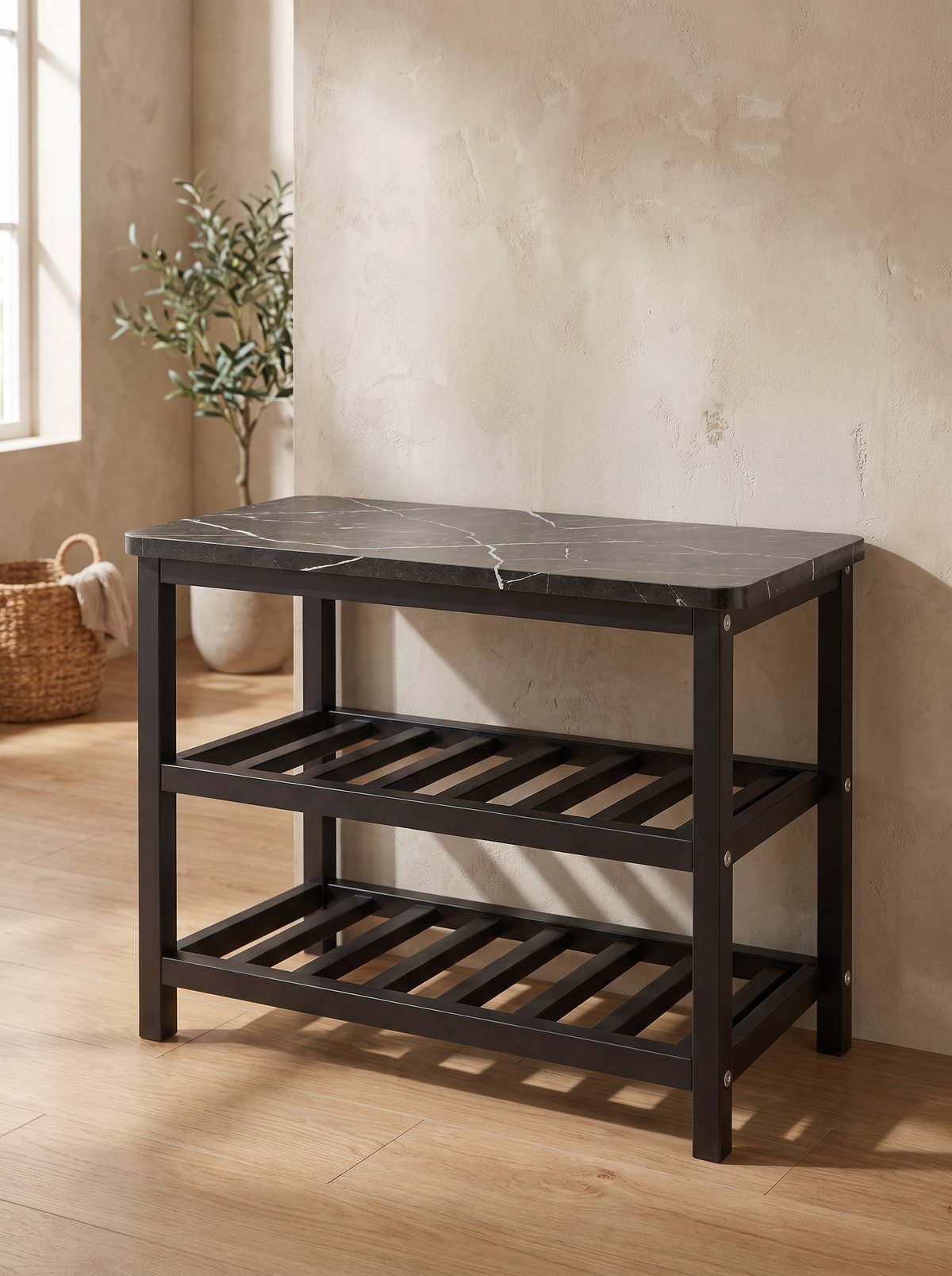 A low matte black steel shoe rack with a white-veined marble-look top and two open shelves standing against an entryway wall