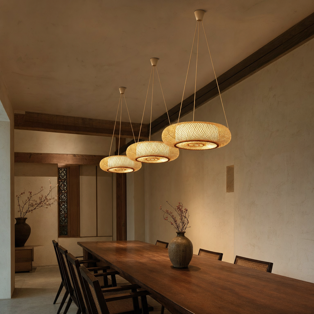 Three bamboo drum pendant lights on three cords each above a long walnut dining table