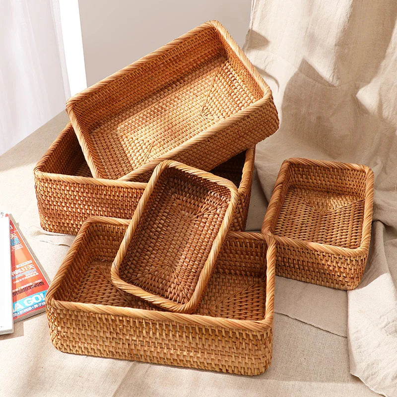 Five handwoven rattan baskets in different sizes stacked on linen