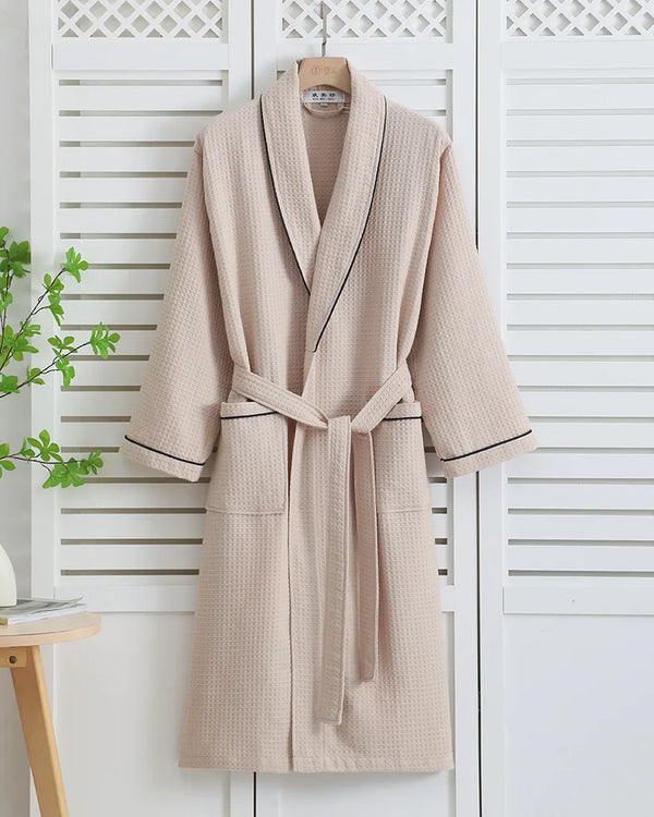 Khaki waffle bathrobe with dark piping hanging on a white shutter