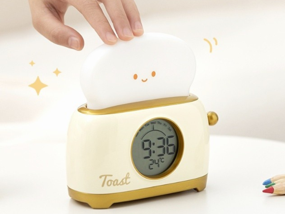 Hand pressing the toast shaped night light on the yellow kids alarm clock