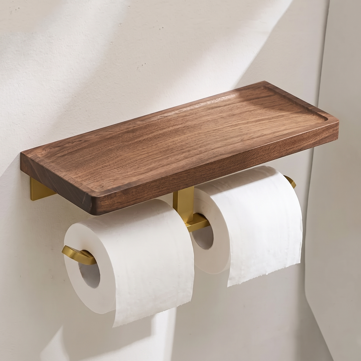Double walnut toilet paper holder with brass tone bar beside a toilet