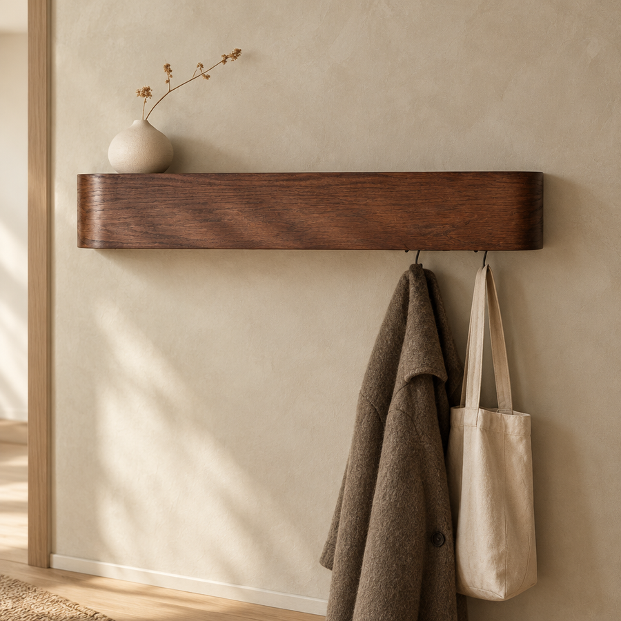 Walnut tone wall shelf with hooks holding a coat and a tote bag in a hallway