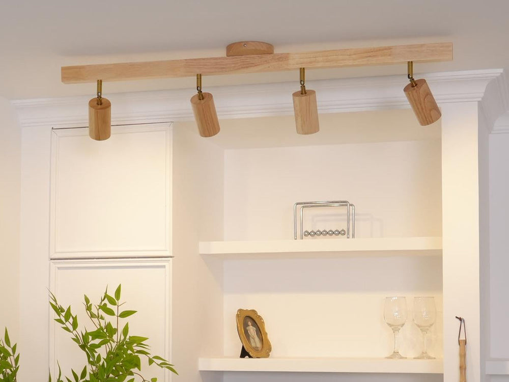 Wood track light with four spot heads on a white ceiling above built-in shelves