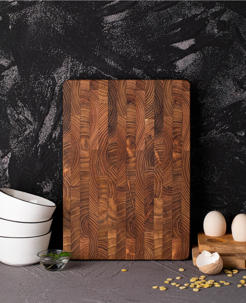 Teak end grain board standing upright against a dark stone wall