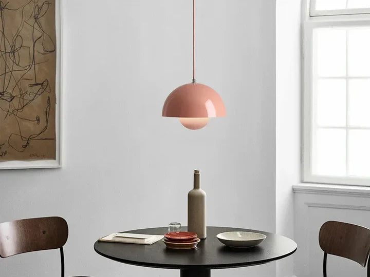 Pink mushroom pendant light hanging over a round black dining table