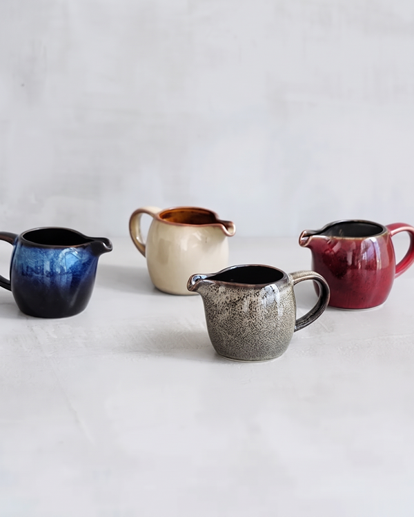 Four small kiln glazed jugs in blue, cream, gray and red