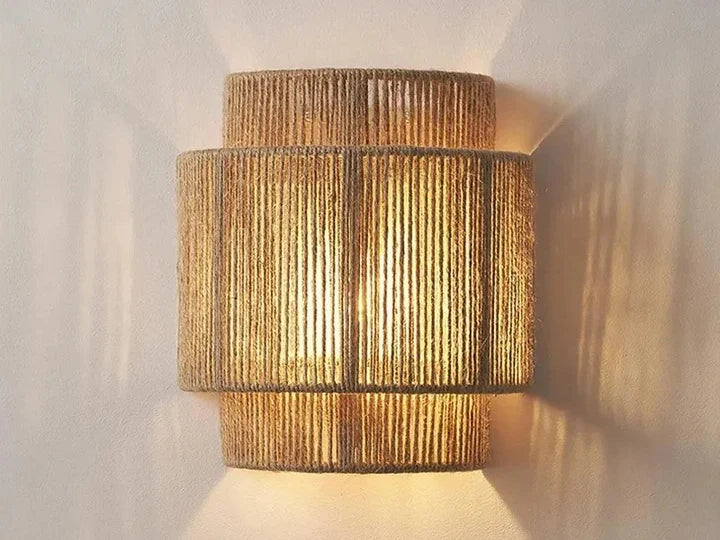 Rattan rope wall sconce switched on, casting light up and down a white wall