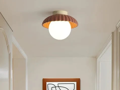 Ribbed flush mount ceiling light with a red shade and glass globe in a hallway