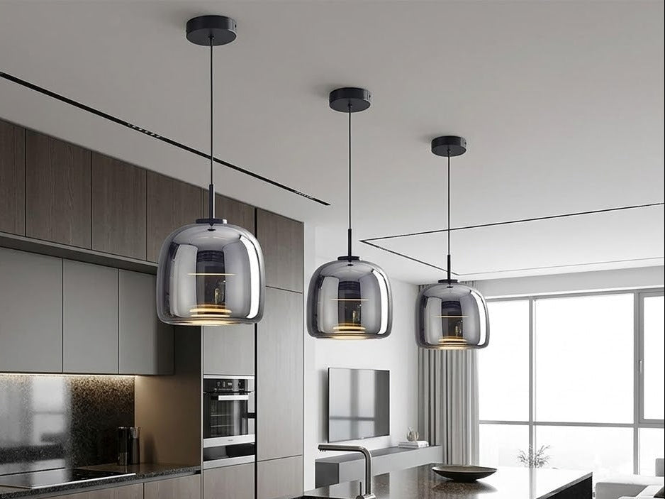 Three gray smoked glass pendant lights hanging over a dark kitchen island
