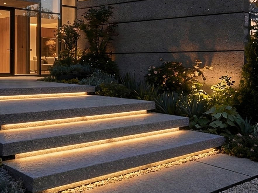 Embedded LED strip lights glowing under the treads of outdoor stone garden steps at dusk
