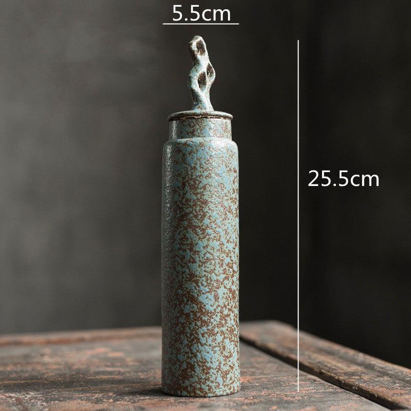 Handmade stoneware tea caddy with airtight ceramic lid beside a filled cup on a linen runner