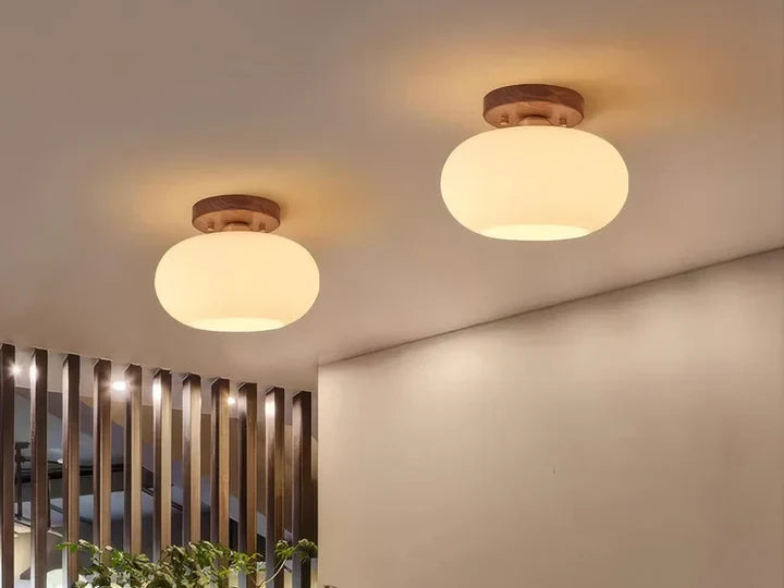 Two walnut and opal glass flush mount ceiling lights lit on a ceiling