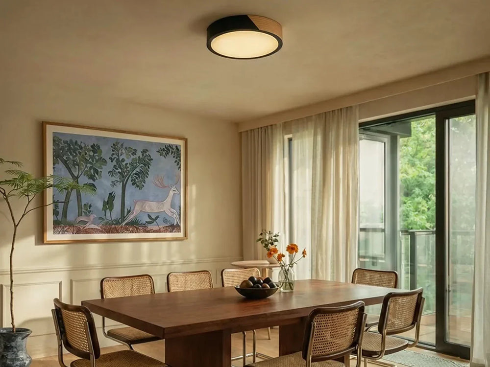 Black round flush mount ceiling light with a wood section above a dining table