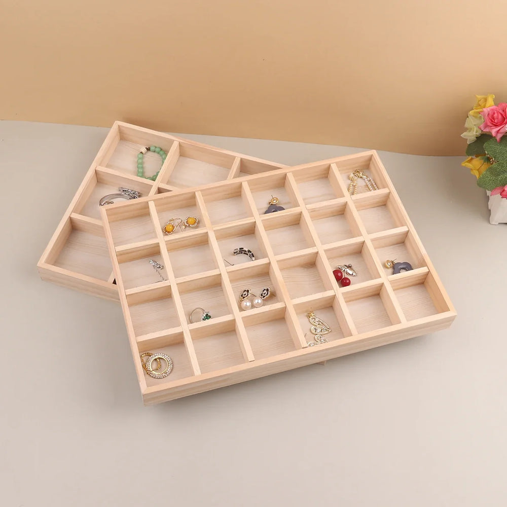Two wooden jewelry trays stacked with earrings and bracelets inside