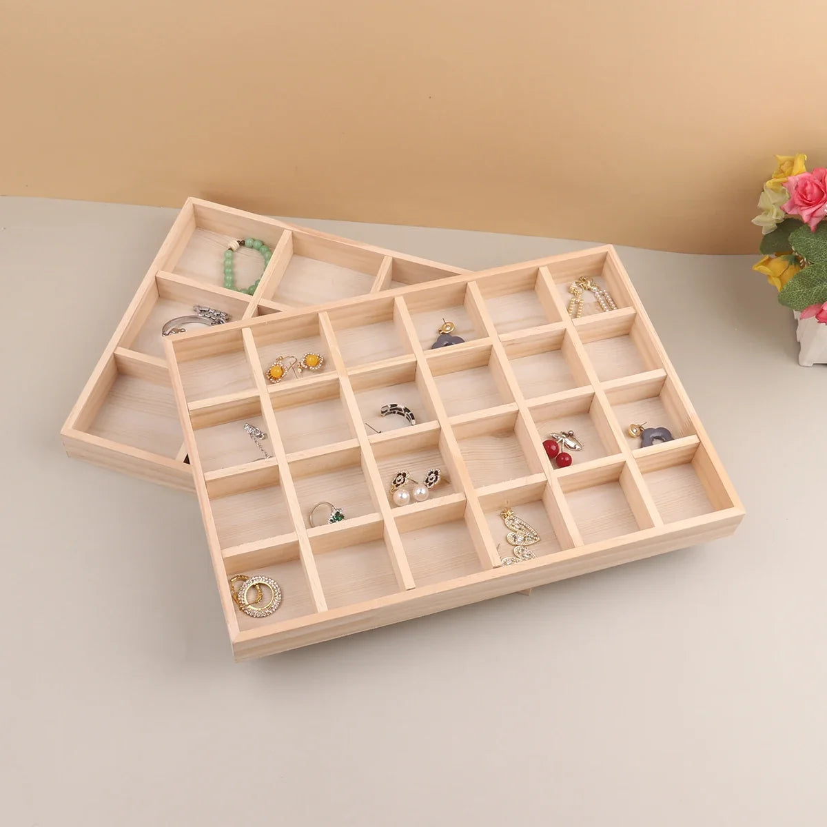 Two wooden jewelry trays stacked with earrings and bracelets inside